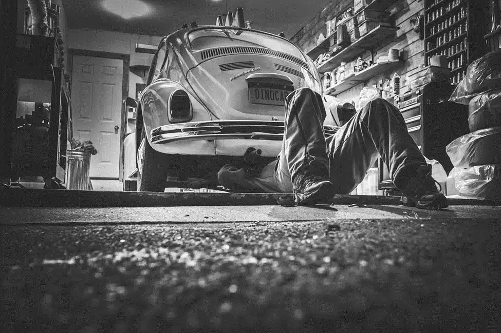 Alt-text: Man in a garage fixing a car