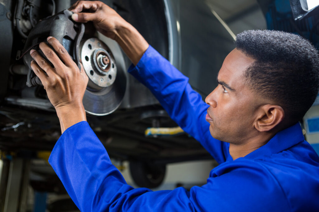 Attentive mechanic fixing a car brake at repair garage