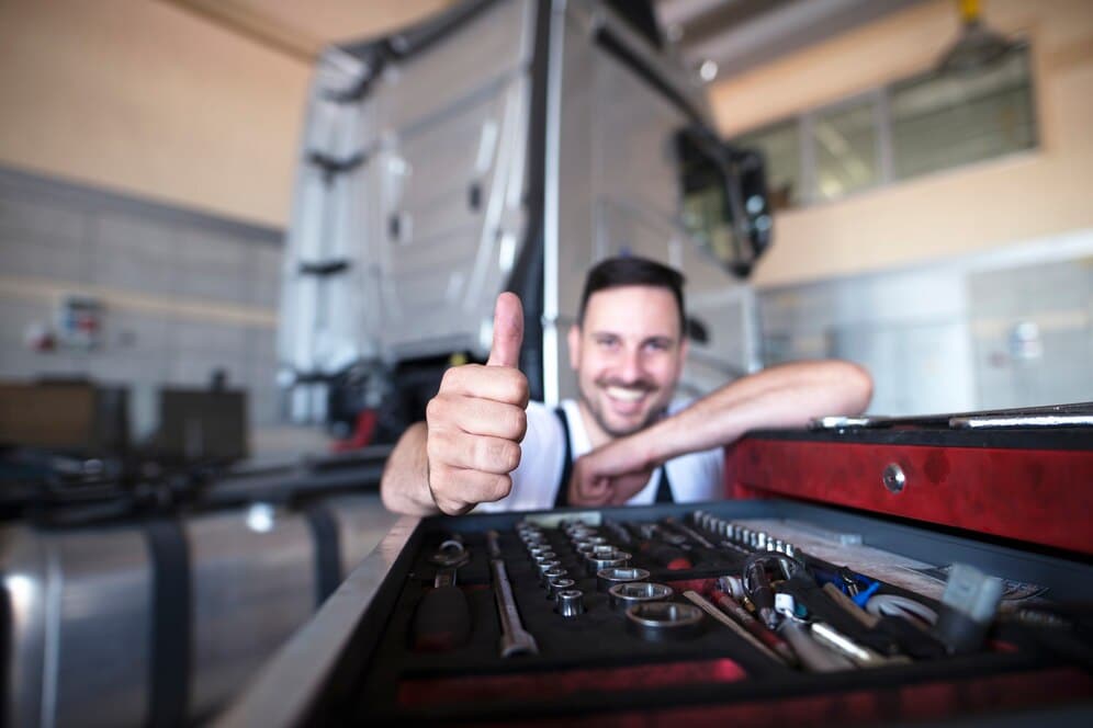 Professional mechanics by the tools cart showing thumbs up