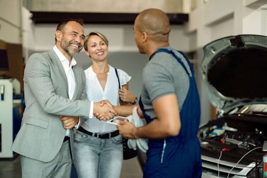 Satisfied customers happily exchanging pleasantries with their mechanic